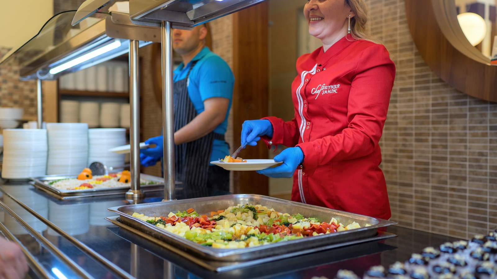 Estudante se serve no self-service de restaurante universitário, foco na redução do desperdício.